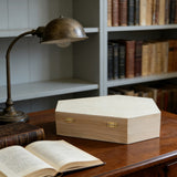 Natural pine wooden pet urn displayed on a desk beside a book